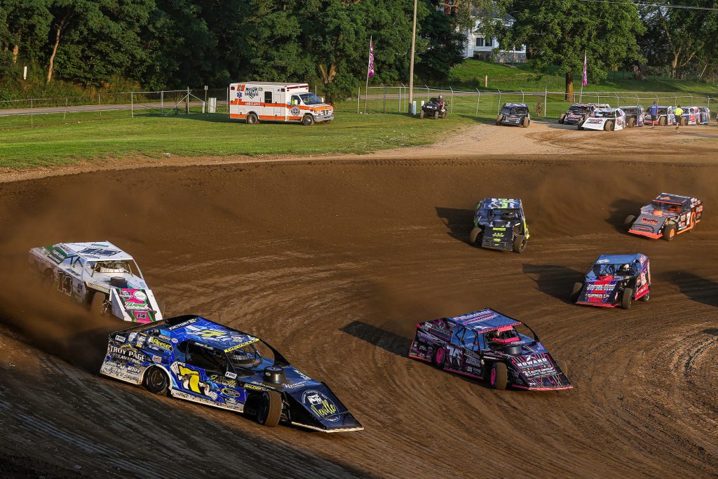 DIRTcar UMP Modifieds racing around a racetrack at a DIRTcar Summit Racing Equipment Modified Nationals event.